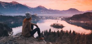 woman hiker sitting on rock gazing at lake and mountains