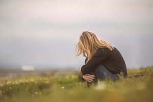 woman sitting in field in fetal position