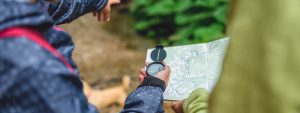 two hikers using compass and map